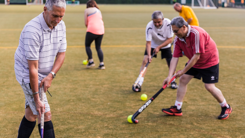 Adults taking part in community walking hockey session